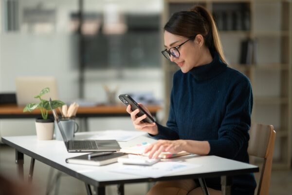 Asian Businesswoman Sitting And Reading Phone At The Office